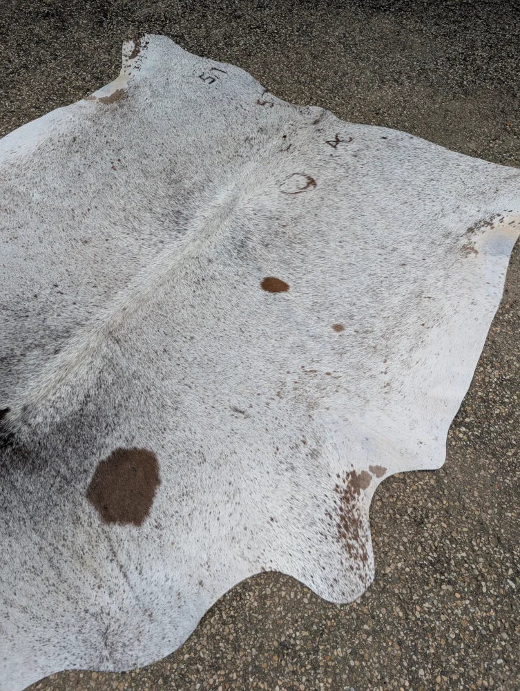 Extra large hello#14 cowhide rug with white and natural brown spots featuring unique characteristics and textured surface