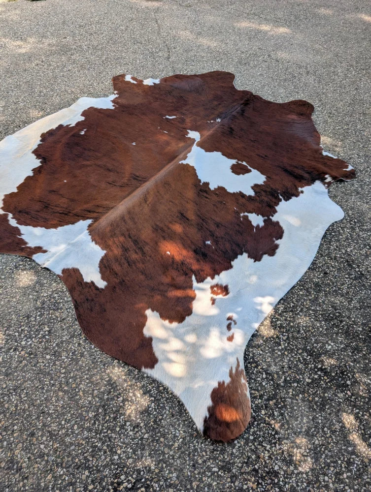 Large cowhide rug with brown and white natural irregular patches showcasing unique characteristics and rustic charm