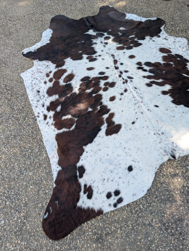 Large brown and white spotted cowhide rug with natural fur texture offering unique characteristics and rustic charm