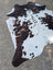 Large brown and white spotted cowhide rug with natural fur texture offering unique characteristics and rustic charm