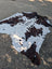 Large brown and white cowhide rug with unique dark brown patches and rustic charm sized 87 x 79 inches