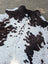Large cowhide rug with white and brown spots and natural irregular edge showing rustic charm and unique characteristics