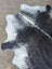 Black and white large cowhide rug with natural irregular edges showcasing unique characteristics and rustic charm
