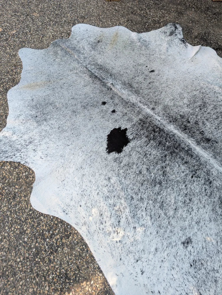A large cowhide rug with white and gray natural irregular edges showcasing unique characteristics and rustic charm