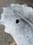 A large cowhide rug with white and gray natural irregular edges showcasing unique characteristics and rustic charm