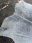 A large cowhide rug in white and gray speckled with unique characteristics and rustic charm in an irregular shape