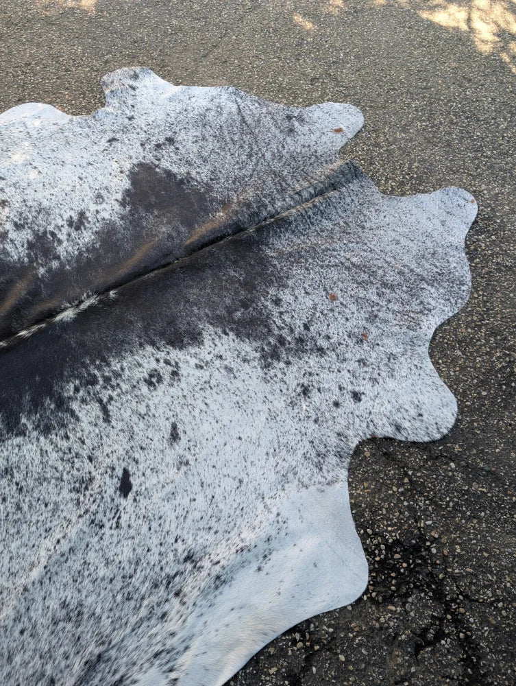 Large black and white speckled cowhide rug with unique characteristics and rustic charm natural irregular edge