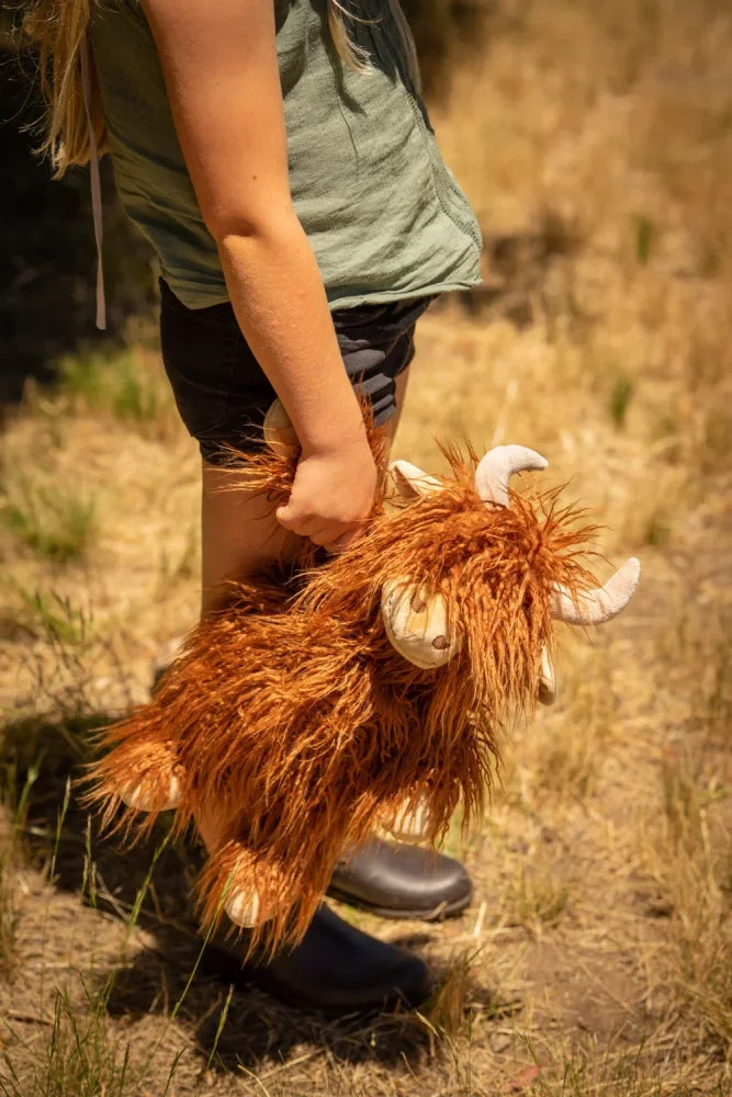 A plush orange highland cow toy named henry with white horns and hooves perfect for cuddling and decor