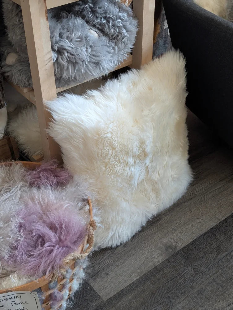 Cozy white fluffy faux fur pillow with beaded trim on Canadian sheep’s wool pet bed