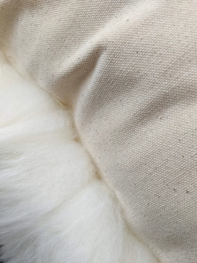 Cream-colored quilted cushion with white fur trim, stuffed with Canadian sheep’s wool