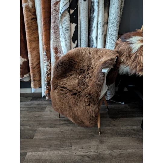 A plush extra large british brown sheepskin rug draped over a chair measuring 53 by 31 inches