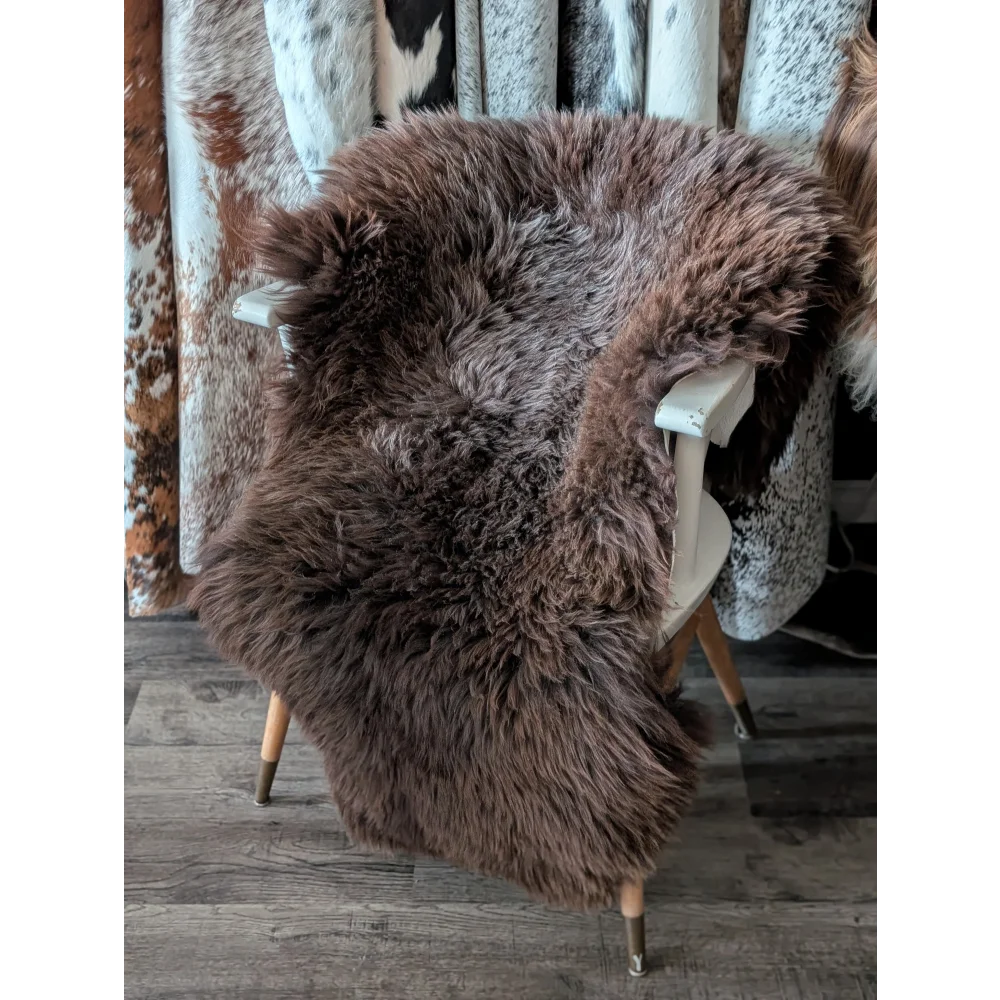 A plush brown angus oliver sheepskin rug draped over a white chair featuring extra large british sheepskin quality from canada