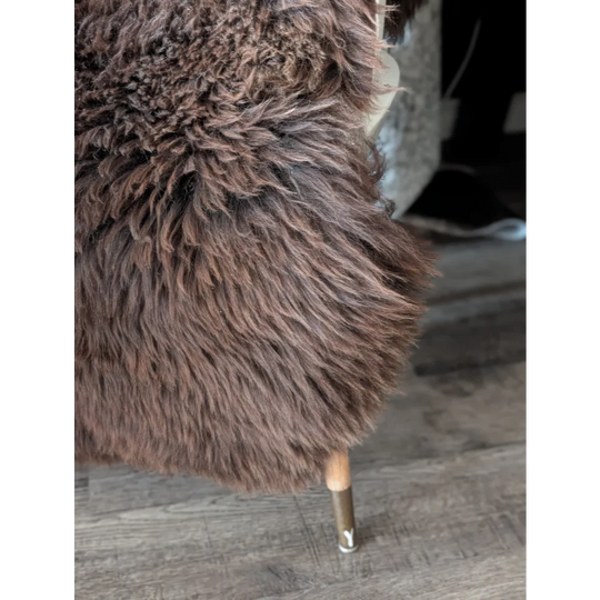 A plush dark brown angus oliver sheepskin chair with soft curly fur and wooden legs, perfect for canada homes with sheepskin rugs