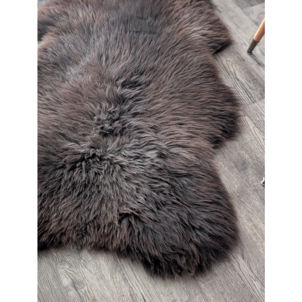 A plush extra large british sheepskin rug in dark gray with thick natural fur texture measuring 52 by 33 inches