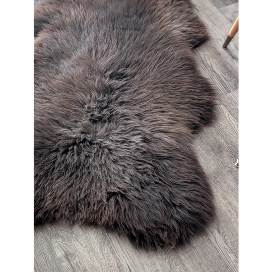 A plush extra large british sheepskin rug in dark gray with thick natural fur texture measuring 52 by 33 inches