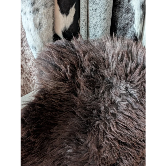 A plush extra large british sheepskin rug in dark brown with long thick curly fibers perfect for cozy spaces