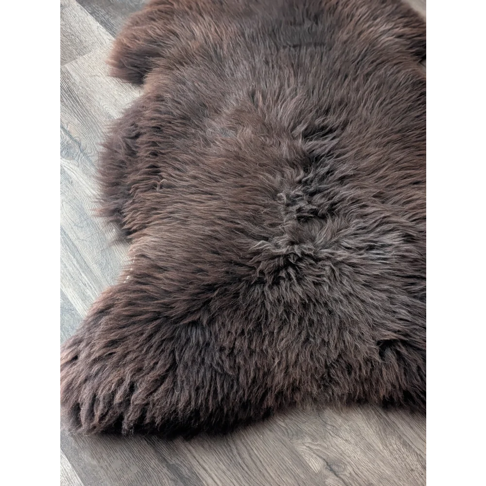 A plush extra large british sheepskin rug in dark brown with soft dense fur texture measuring 52 x 33 inches