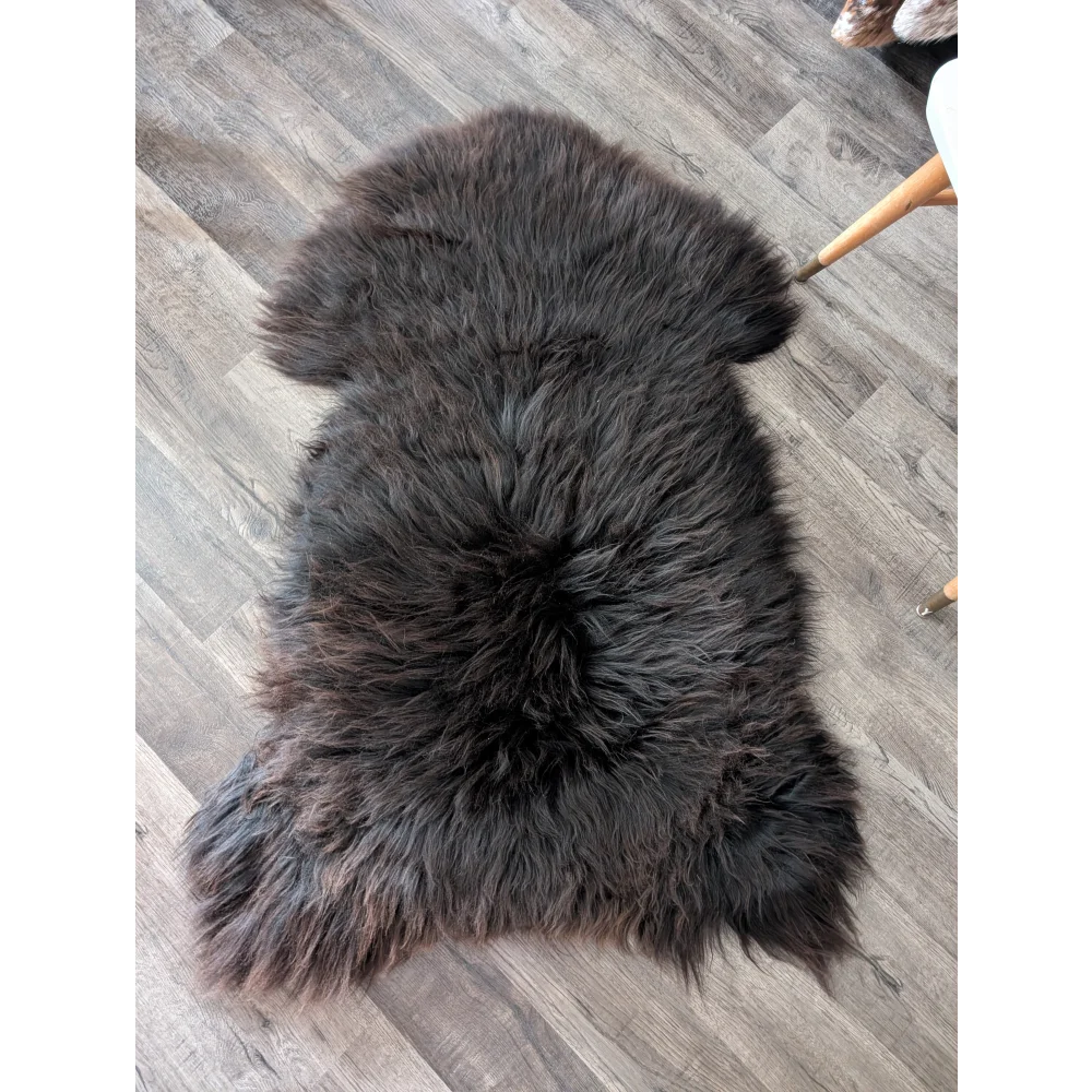 A plush dark gray angus oliver british sheepskin rug with thick fluffy texture and natural edges from canada