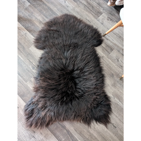 A plush dark gray angus oliver british sheepskin rug with thick fluffy texture and natural edges from canada