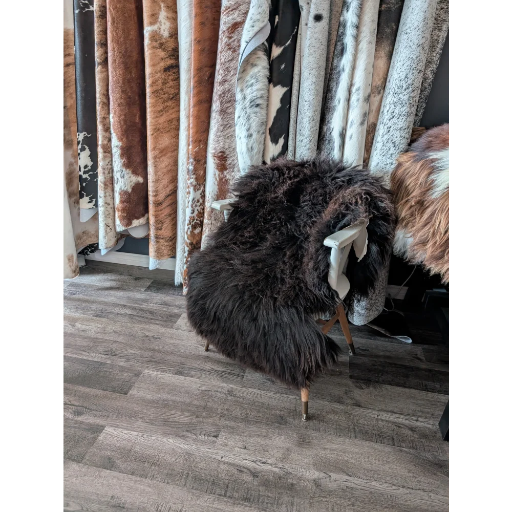 A plush dark brown angus oliver sheepskin rug draped over a white wooden chair perfect for canadian homes