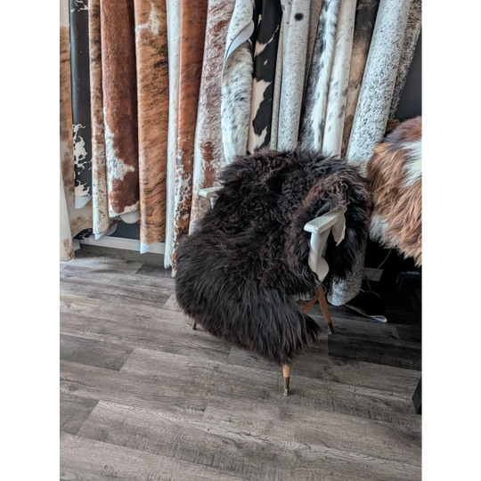 A plush dark brown angus oliver sheepskin rug draped over a white wooden chair perfect for canadian homes