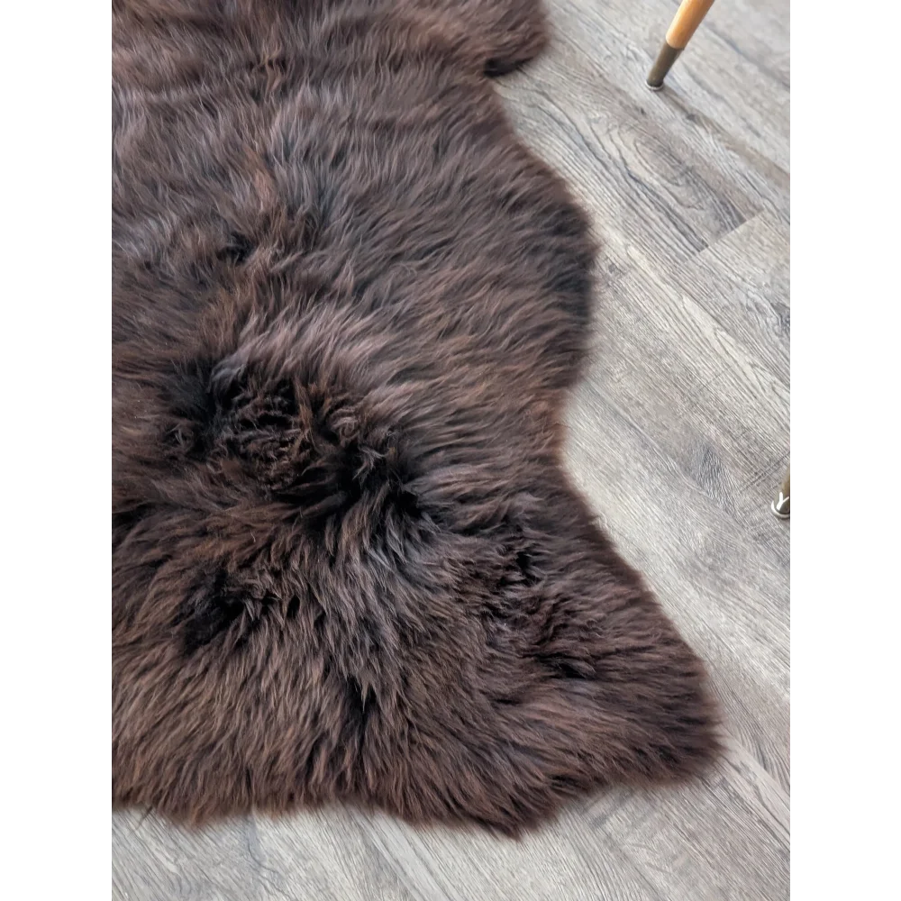 A plush extra large british sheepskin rug in dark brown with soft dense fur and a natural irregular shape