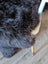 A plush dark gray british isles sheepskin rug with thick shaggy faux fur draped over a chair edge
