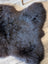 A plush dark gray british isles sheepskin rug with soft dense fur and natural irregular shape measuring 53 by 27 inches