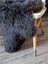 Dark gray plush british isles sheepskin rug draped over white stool with wooden legs for cozy decor