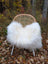 A cozy white long wool icelandic sheepskin throw draped over a woven rattan chair with metal legs