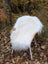White fluffy ice#1 48 x 32 wool icelandic sheepskin throw draped over a woven wicker chair with white metal legs