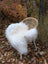 White fluffy long wool icelandic sheepskin throw draped over a woven rattan chair with white metal legs
