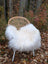 A cozy white long wool icelandic sheepskin throw draped over a woven rattan chair with metal legs