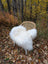 White fluffy wool icelandic sheepskin throw draped over woven rattan chair for cozy decor