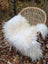 A plush off-white long wool icelandic sheepskin rug draped over a wicker chair showing curly fibers
