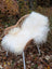 A plush white curly long wool icelandic sheepskin throw draped over a woven wicker chair for cozy use