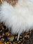 White fluffy wool icelandic sheepskin throw blanket draped over a wicker chair for cozy decor