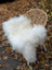 A plush off-white long wool icelandic sheepskin throw draped over a wicker chair for cozy comfort