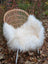 A plush white long wool icelandic sheepskin throw draped over a woven rattan chair with metal legs