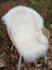 Fluffy white long wool icelandic sheepskin rug draped over a wicker chair for cozy decor