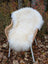 Off-white long wool icelandic sheepskin rug with curly fibers draped over a wicker chair for cozy decor