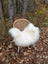 A cozy white long wool icelandic sheepskin throw draped over a woven rattan chair with metal legs outdoors