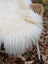A plush off-white long wool icelandic sheepskin throw draped over a wicker chair for cozy decor