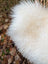 A plush white curly long wool icelandic sheepskin throw blanket with soft voluminous texture measuring 48 x 31 inches