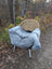 Gray faux fur throw with wool icelandic texture draped over a wicker chair with white metal legs