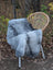 Gray faux fur throw blanket draped over wicker chair made from long wool icelandic sheepskin in natural grey