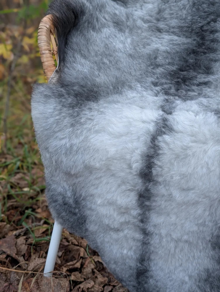 Gray faux fur chair with woven wicker armrest white plastic legs made from long wool icelandic sheepskin