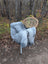 Gray faux fur icelandic sheepskin throw draped over wicker chair with white metal legs showcasing long wool icelandic texture