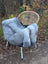 A plush gray long wool icelandic sheepskin throw draped over a wicker chair with white metal legs