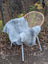 A soft natural grey icelandic sheepskin rug with long wool icelandic draped over a wicker chair with white metal legs